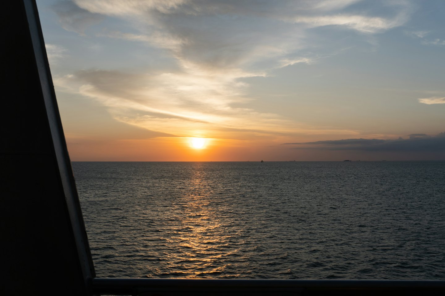 Sunset reflecting on the ocean from a boat deck.