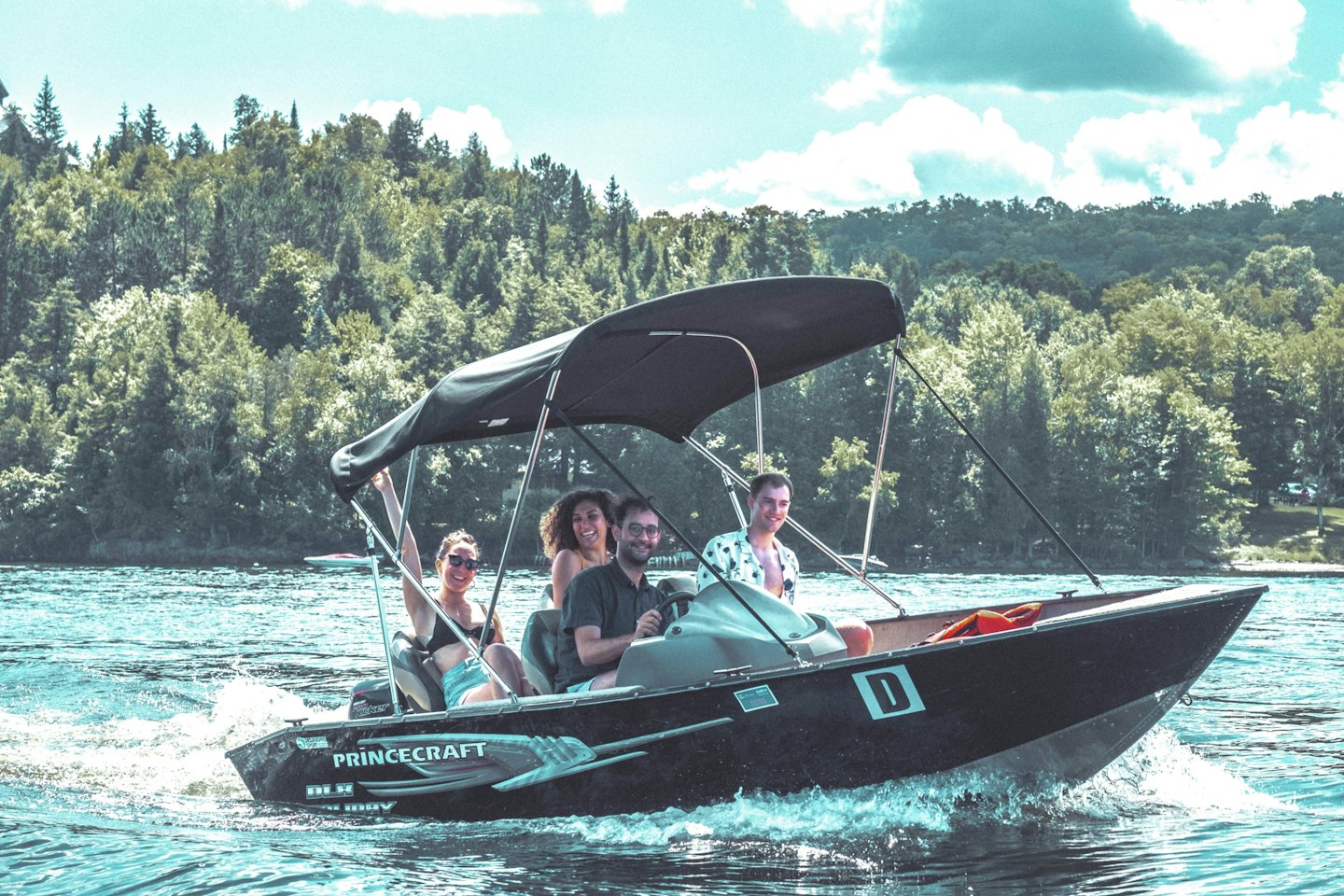Four friends enjoy a boat ride on calm blue water.