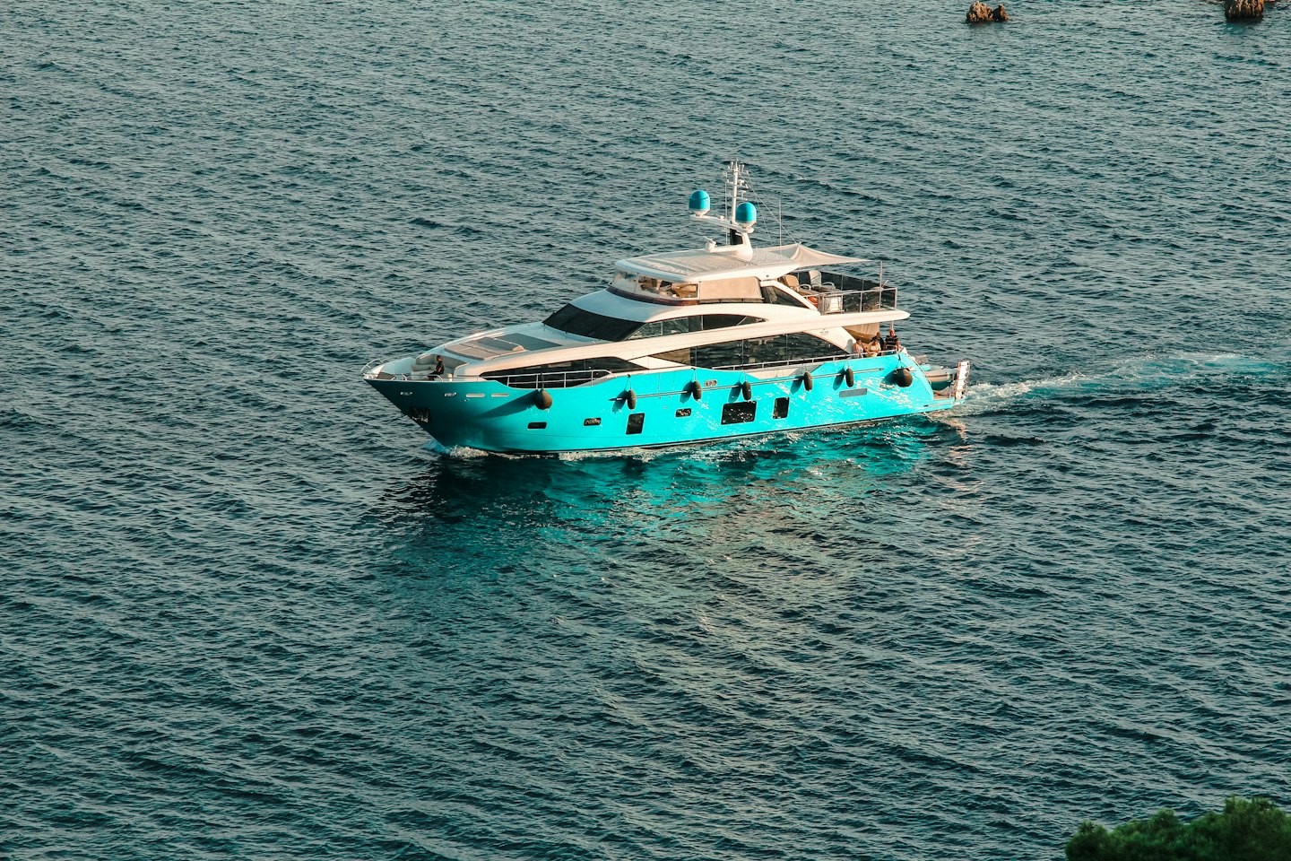 A luxury yacht cruises through coastal waters leaving a wake.