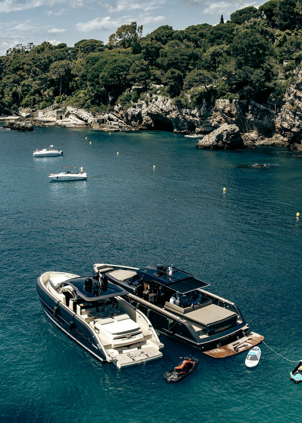 Two luxury yachts docked in a calm turquoise bay.