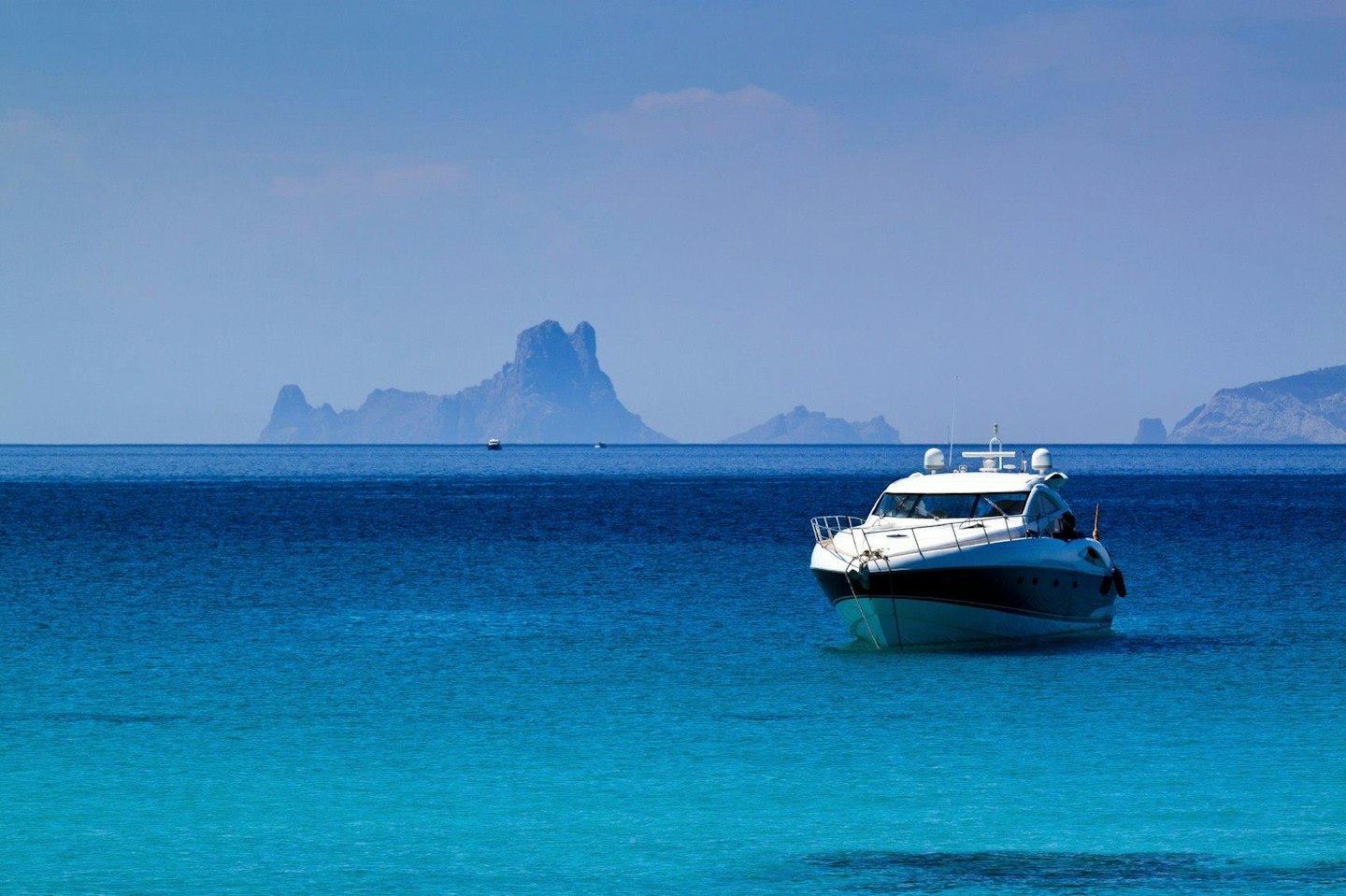 A black and white motorboat floating on clear blue ocean water.